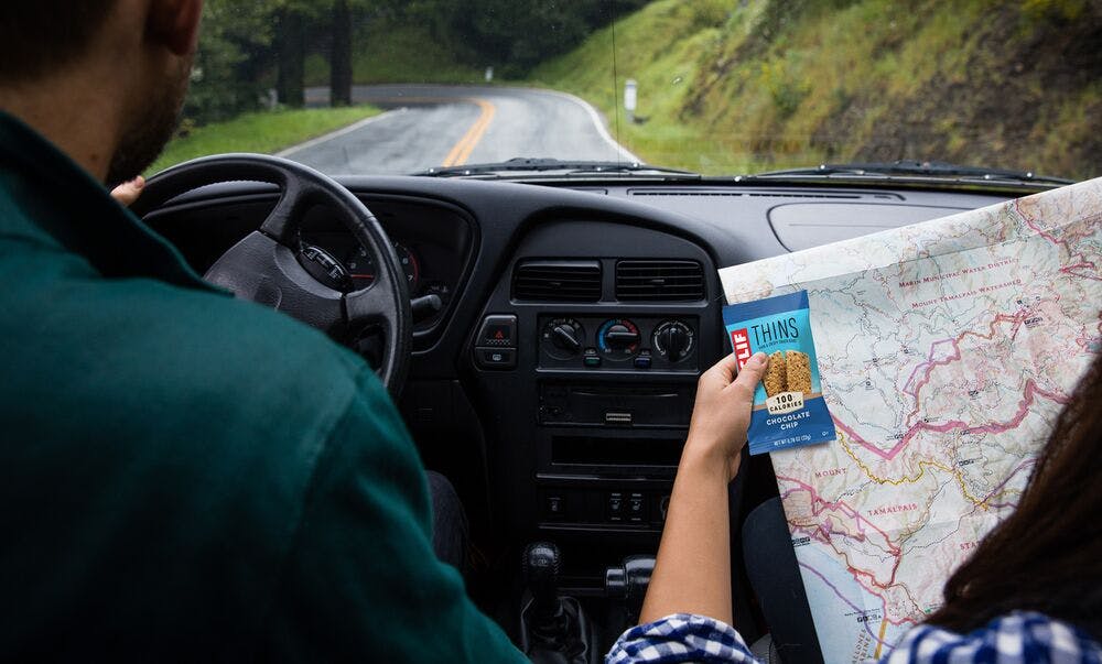 Two People Driving Eating CLIF Thins as Road Trip Snack